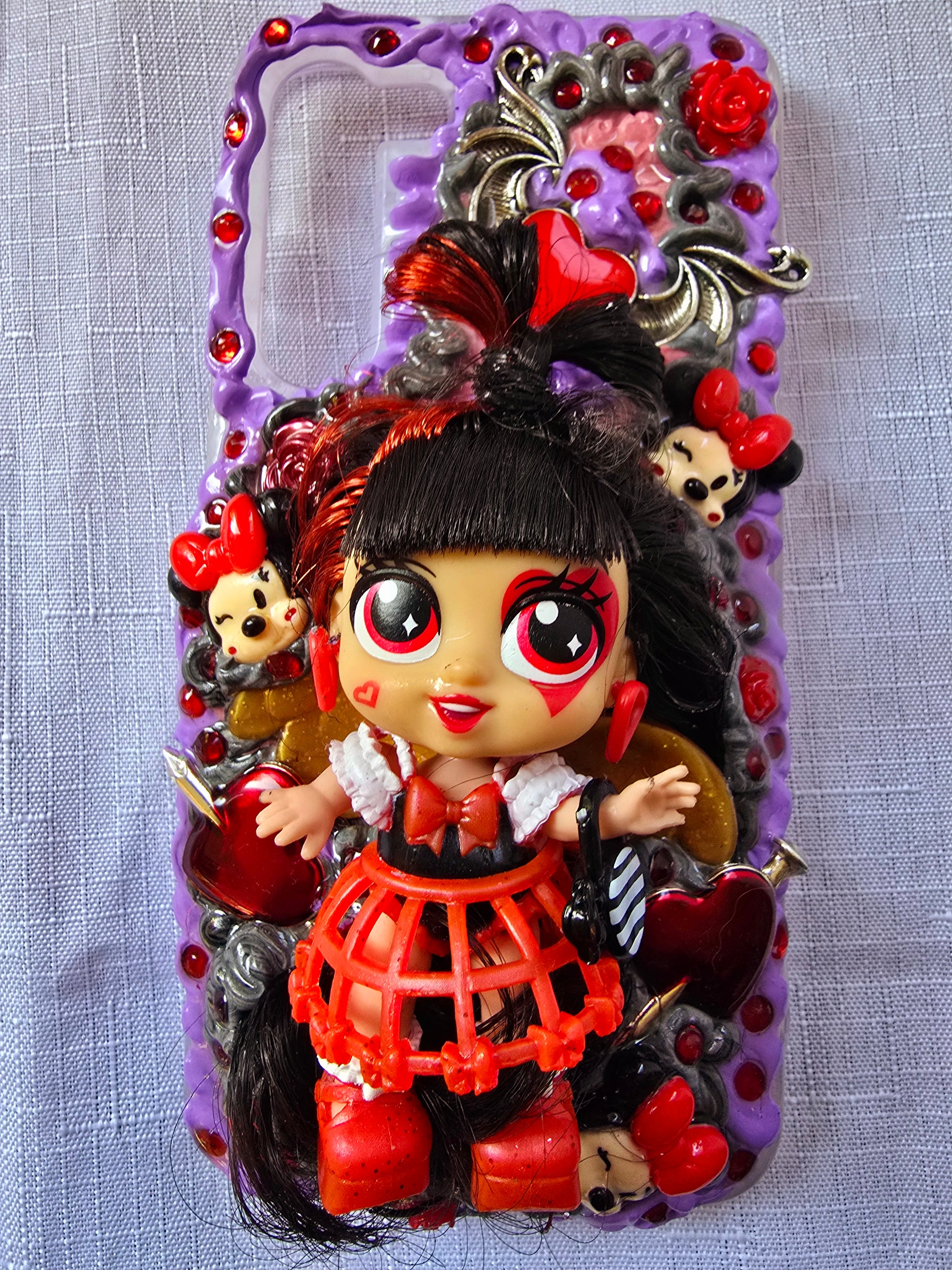Handmade Samsung S23 Plus phone case with gothic and doll-inspired design, featuring red and black accents, heart charms, and 3D figure on a purple base.